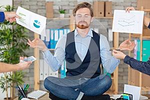 zen businessman doing yoga meditation on desk ignoring distractions