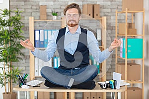zen businessman doing yoga meditation on office desk