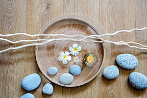 Zen flow of pebbles, candle, flowers and twigs over wood
