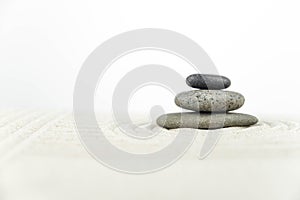 Zen garden. Pyramids of white and gray zen stones on the white sand with abstract wave drawings.