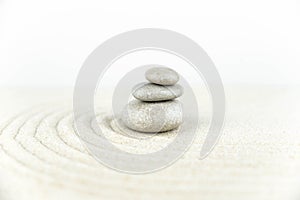 Zen garden. Pyramids of white and gray zen stones on the white sand with abstract wave drawings.