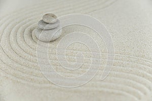 Zen garden. Pyramids of white and gray zen stones on the white sand with abstract wave drawings.