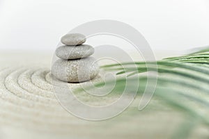 Zen garden. Pyramids of white and gray zen stones on the white sand with abstract wave drawings.