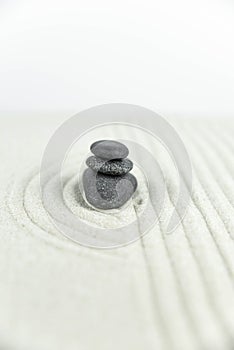 Zen garden. Pyramids of white and gray zen stones on the white sand with abstract wave drawings.