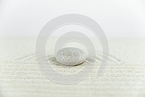 Zen garden. Pyramids of white and gray zen stones on the white sand with abstract wave drawings.