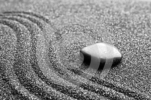 Zen garden stone on black sand with pattern