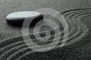 Zen garden stone on black sand with pattern, closeup