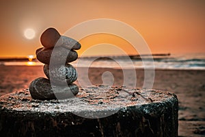 Zen-like stack of stones standing in harmony against the radiant sunset at the Baltic Sea