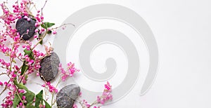 Zen pubbles with pink flowers on white table.