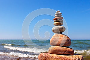 Zen pyramid of balanced stones on a background of the summer sea and blue sky