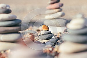 Zen pyramid of spa stones on the blurred sea background. Sand on a beach. Sea shores. Place for text.