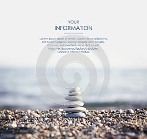 Zen pyramid of spa stones on the blurred sea background. Sand on a beach. Sea shores. Web article template. Long header banner.