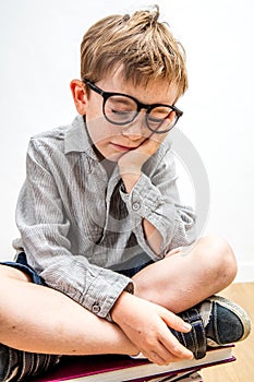 Zen relaxed little boy with freckles sitting on books sleeping