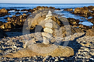 Zen rocks balanced stone stack on sand beach and rocky Pacific oceancoast