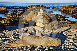 Zen rocks balanced stone stack on sand beach and rocky Pacific oceancoast