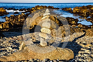 Zen rocks balanced stone stack on sand beach and rocky Pacific oceancoast