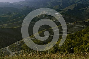 Zen serenity mountain landscape - high lush green mountain ridges , serpentine road and village away in cold morning mist