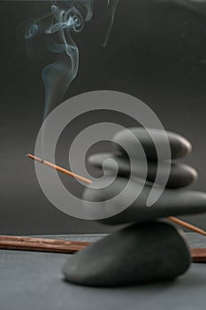 Zen spa basalt stones and green bamboo leaves and incense on black background.