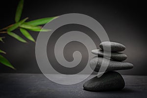 Zen spa basalt stones and green bamboo leaves on black background. Wellness and relaxation.