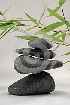 Zen spa basalt stones and green bamboo leaves on white background. Wellness and relaxation.