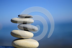 Zen spa stones with blue water and sky. Balanced stones background, copy space. Spa symbol. Balancing stones. Symbol of stability.