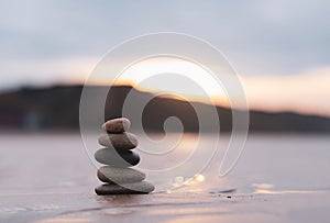 Zen stack stone on sea sand beach with blurry sunset background,Image Landscape pebble rock tower pyramid concept for stability,