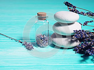 Zen stack stones on a blue wooden background, lavender seeds in a bottle and lavender branches nearby