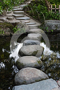 Zen stone path in a Japanese Garden across a tranquil pond in Ok