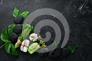 Zen stones and leaves with water drops. Spa background with spa accessories on a dark background. Top view. Free space