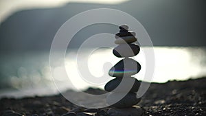 Zen stones on the sea beach. Silhouette of a cairn on a pebble beach at sunset. Abstract bokeh with sea in the