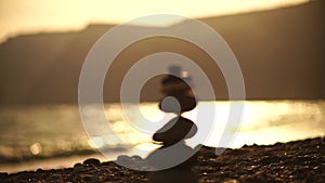 Zen stones on the sea beach. Silhouette of a cairn on a pebble beach at sunset. Abstract bokeh with sea in the