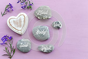 zen stones with the words Mind body soul. purple wooden background