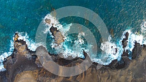 zenithal aerial drone view of waves crashing against cliffs photo