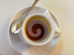Zenithal view of a finished coffee cup, next to a teaspoon photo