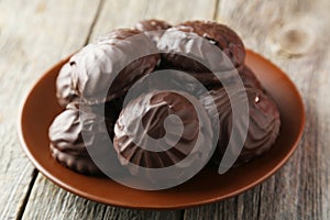 Zephyr in chocolate on plate on the grey wooden background