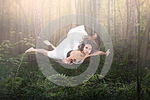 Zero gravity. Young beautiful woman flying in a dream. Forest green and glow