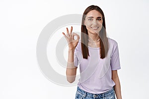 Zero problems, alright. Young smiling woman shows okay OK sign and nod in approval, like and agree gesture, approve