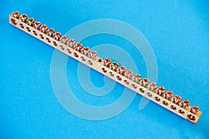 Zero tire neutral terminal. Panel electrical equipment. Photo of a copper zero busbar on a blue background