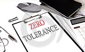 ZERO TOLERANCE text on paper clipboard with chart and notebook on withe background