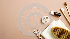 Zero waste bathroom accessories on brown background. Eco friendly ear sticks, bamboo toothbrushes, spa brush, luffa sponge,