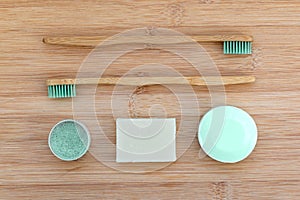 Zero waste bathroom basics. Bamboo toothbrushes, solid toothpaste in metal tin, solid shampoo and soap on wood. Plasti