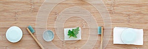 Zero waste bathroom web banner with copy space. Bamboo toothbrushes, solid toothpaste, solid shampoo and soap on wood background.