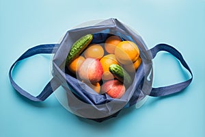 Zero waste concept. Blue shopping textile bag with fresh orange and vegetables. Space for text