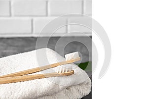 Zero waste concept. Eco natural bamboo toothbrush, white frame and towel on grey background with green leaf.