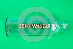 Zero waste concept. Empty glass bottle for zero waste shopping and storage on green background