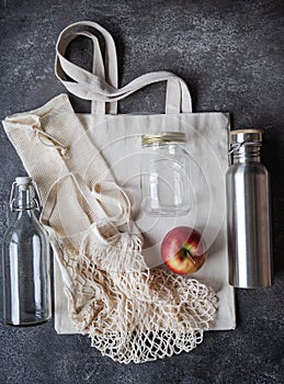 Zero waste concept. Flat lay eco-friendly set. Various bags, bottles and jar on grey background. Top view