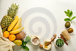 Zero waste concept frame. Food storage. Fruits and cereals in eco textile bags, glass jars with cereals, white background. Copy photo