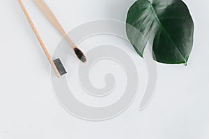 Zero waste concept. Natural eco bamboo toothbrush with monstera leaves white background top view Copy space