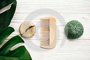 Zero waste concept. Natural eco friendly solid shampoo bar, green konjaku sponge, conditioner, soap on white wood with green mons photo