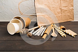 Zero waste concept with wooden utensile and paper cups and bag on wooden background with copy space photo